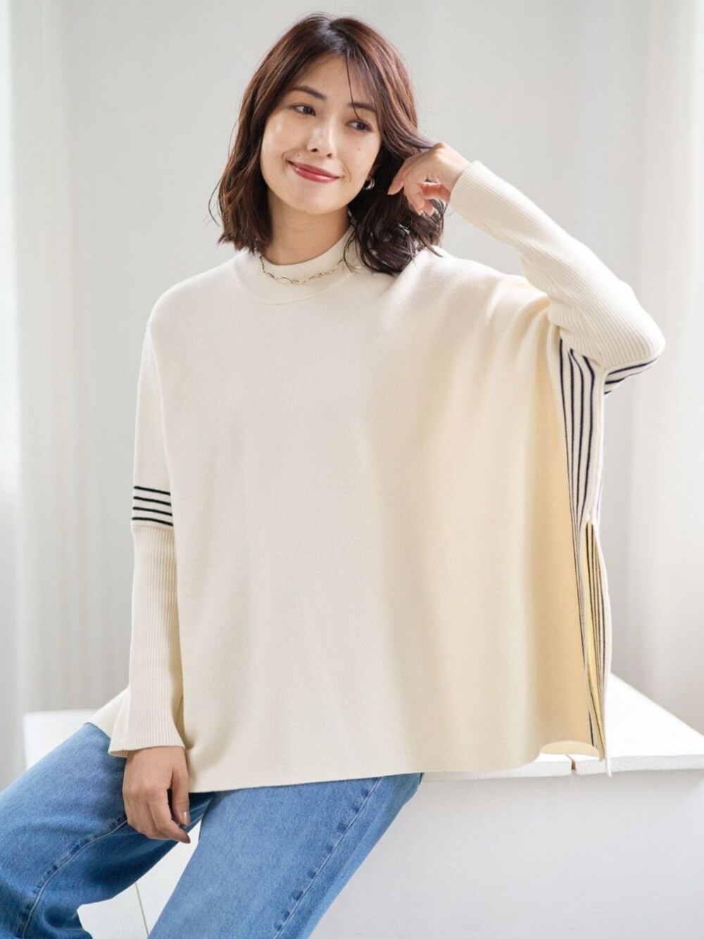 ベージュ系のポンチョを着用したレディースの冬コーディネートの2枚目の写真