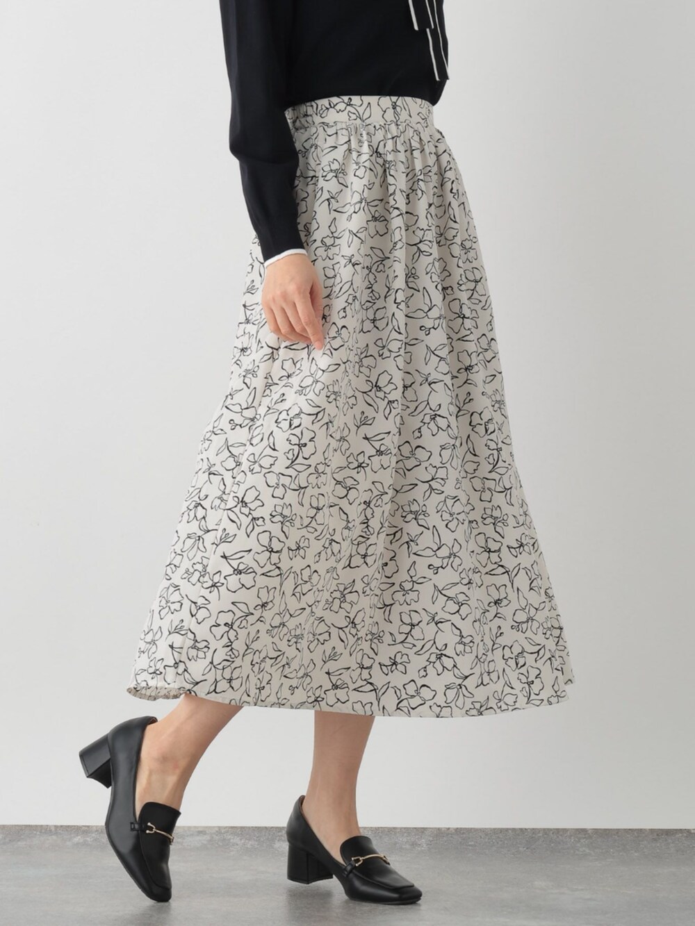 ブラック系のニット/セーター、ベージュ系のスカートを着用したレディースの春コーディネートの3枚目の写真