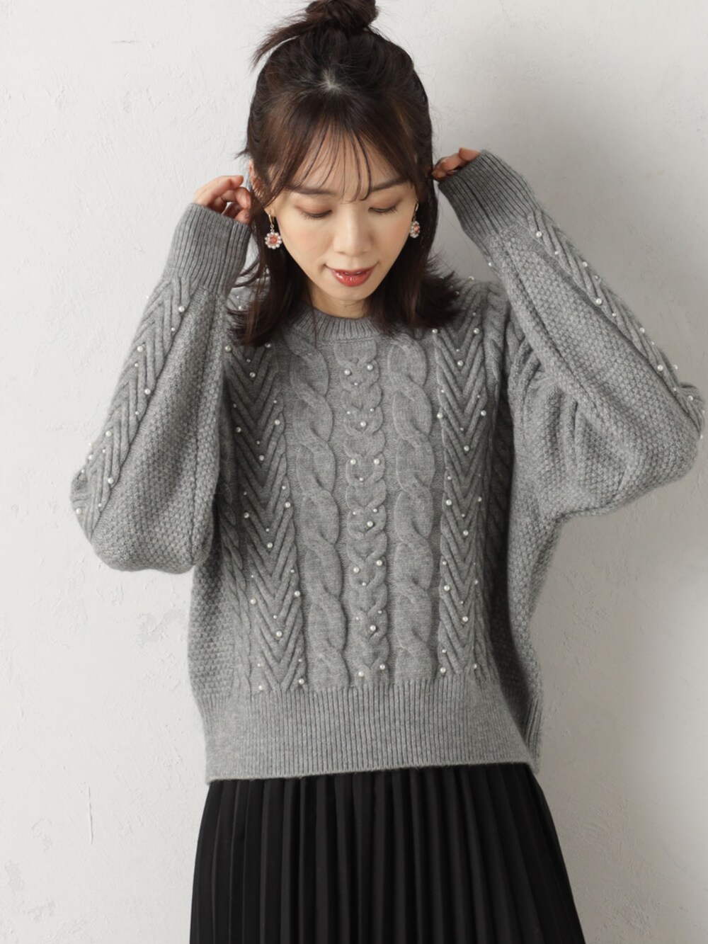 ブラック系のスカート、グレー系のニット/セーターを着用したレディースの冬コーディネートの2枚目の写真