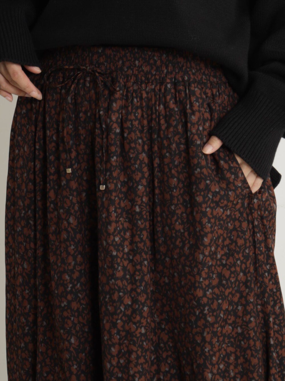 ピンク系のショルダーバッグ、ベージュ系のブーツ、ブラック系のニット/セーターを着用したレディースの冬コーディネートの6枚目の写真