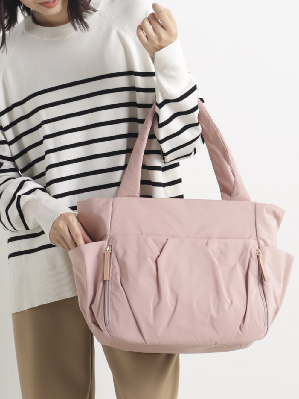 グレー系のニット/セーター、ブラウン系のその他パンツ、ピンク系のトートバッグを着用したレディースの春コーディネートの2枚目の写真