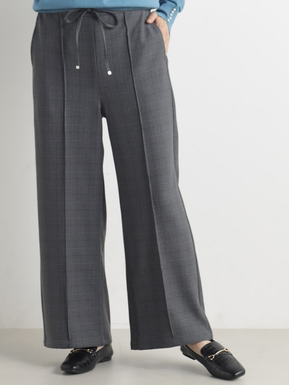 ブルー系のニット/セーター、グレー系のその他パンツを着用したレディースの春コーディネートの2枚目の写真