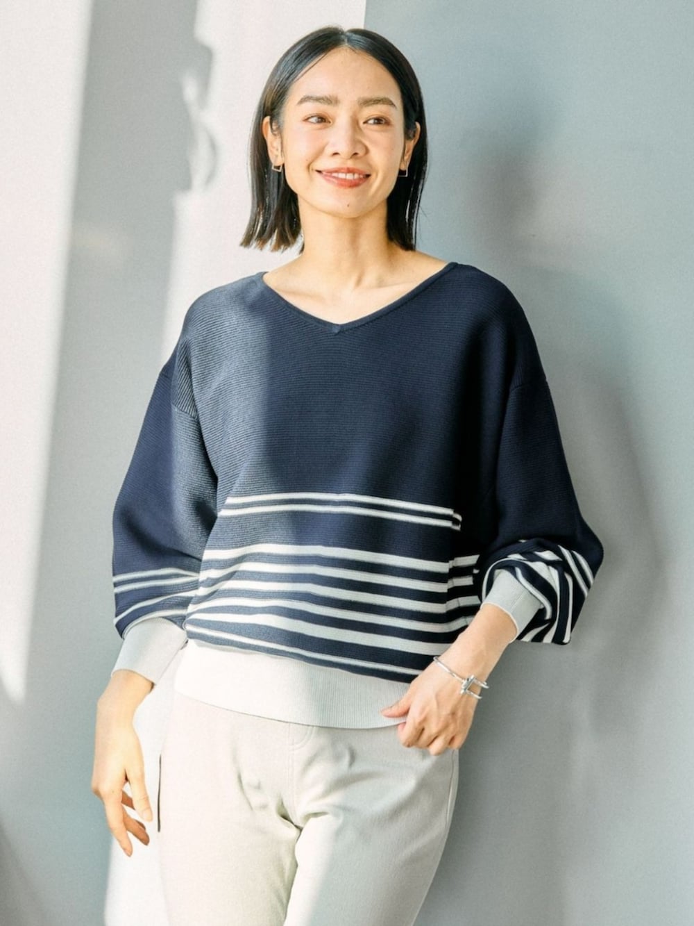 ブルー系のニット/セーターを着用したレディースの春コーディネートの2枚目の写真