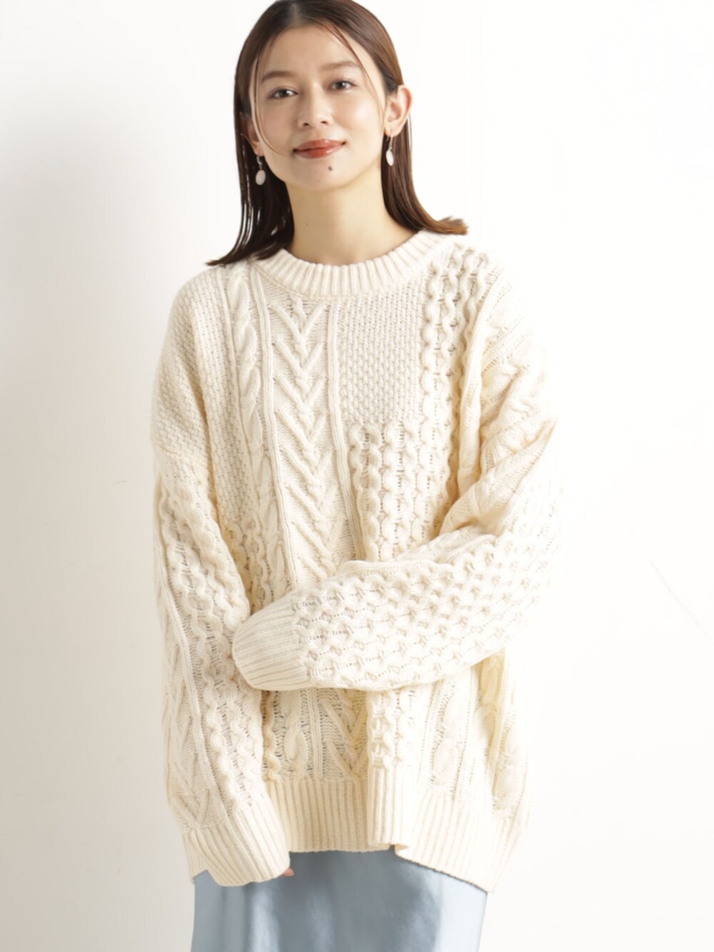 ベージュ系のニット/セーター、ベージュ系のハンドバッグ、ブルー系のスカートを着用したレディースの冬コーディネートの2枚目の写真