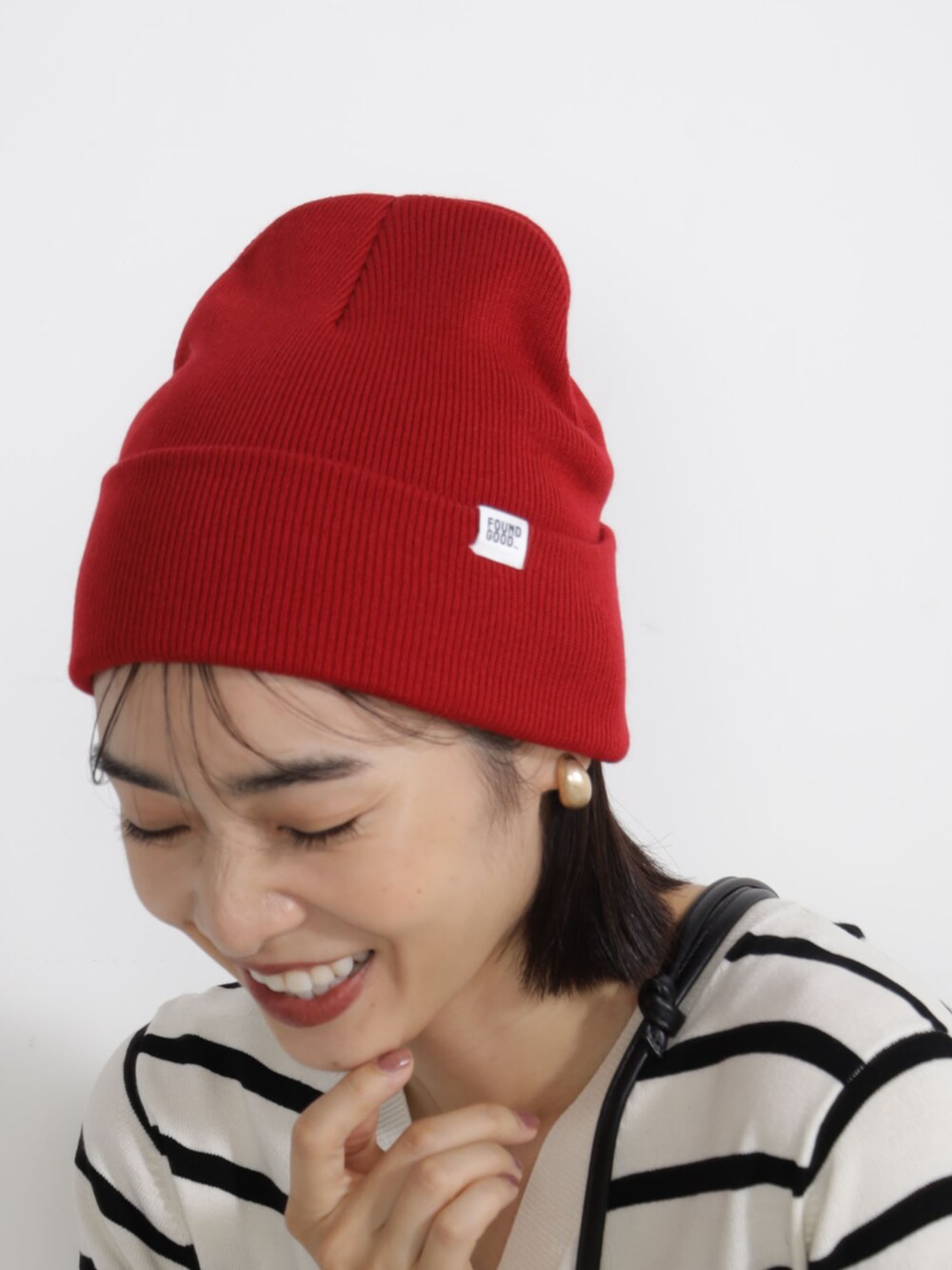 グレー系のニット/セーター、レッド系のキャップを着用したレディースの秋コーディネートの3枚目の写真