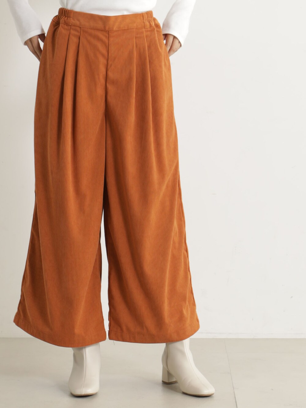 ベージュ系のブーツ、オレンジ系のその他パンツ、ベージュ系のニット/セーターを着用したレディースの冬コーディネートの3枚目の写真