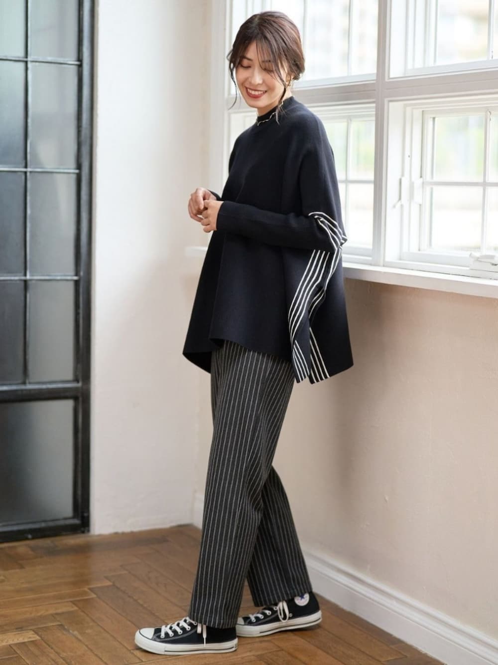 ブラック系のポンチョを着用したレディースの冬コーディネートの2枚目の写真