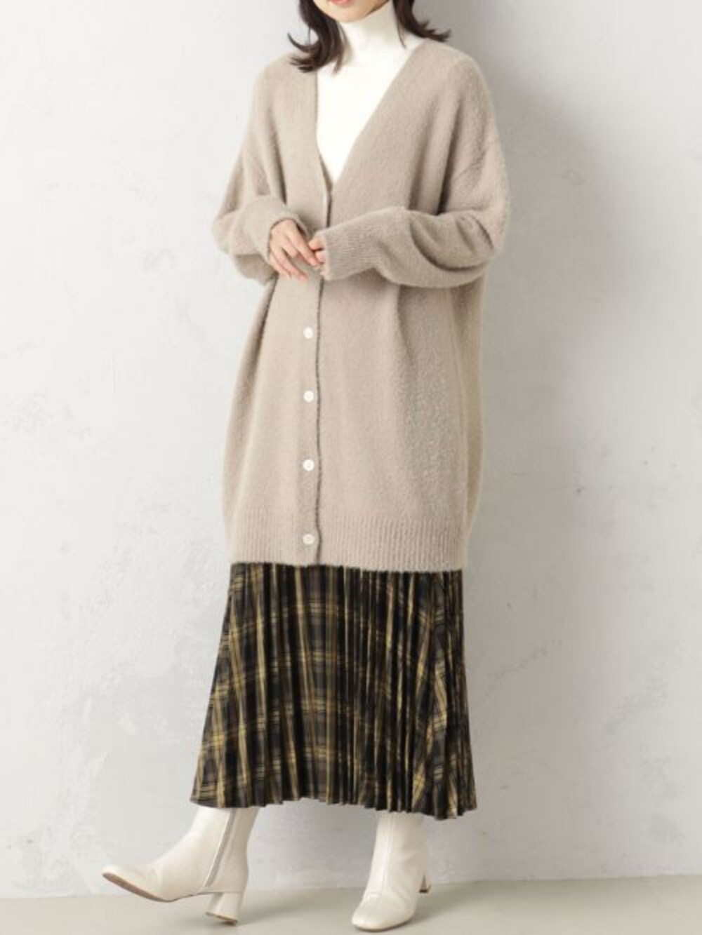 ブラウン系のスカート、ベージュ系のブーツ、ベージュ系のカーディガン/ボレロを着用したレディースの冬コーディネートの2枚目の写真