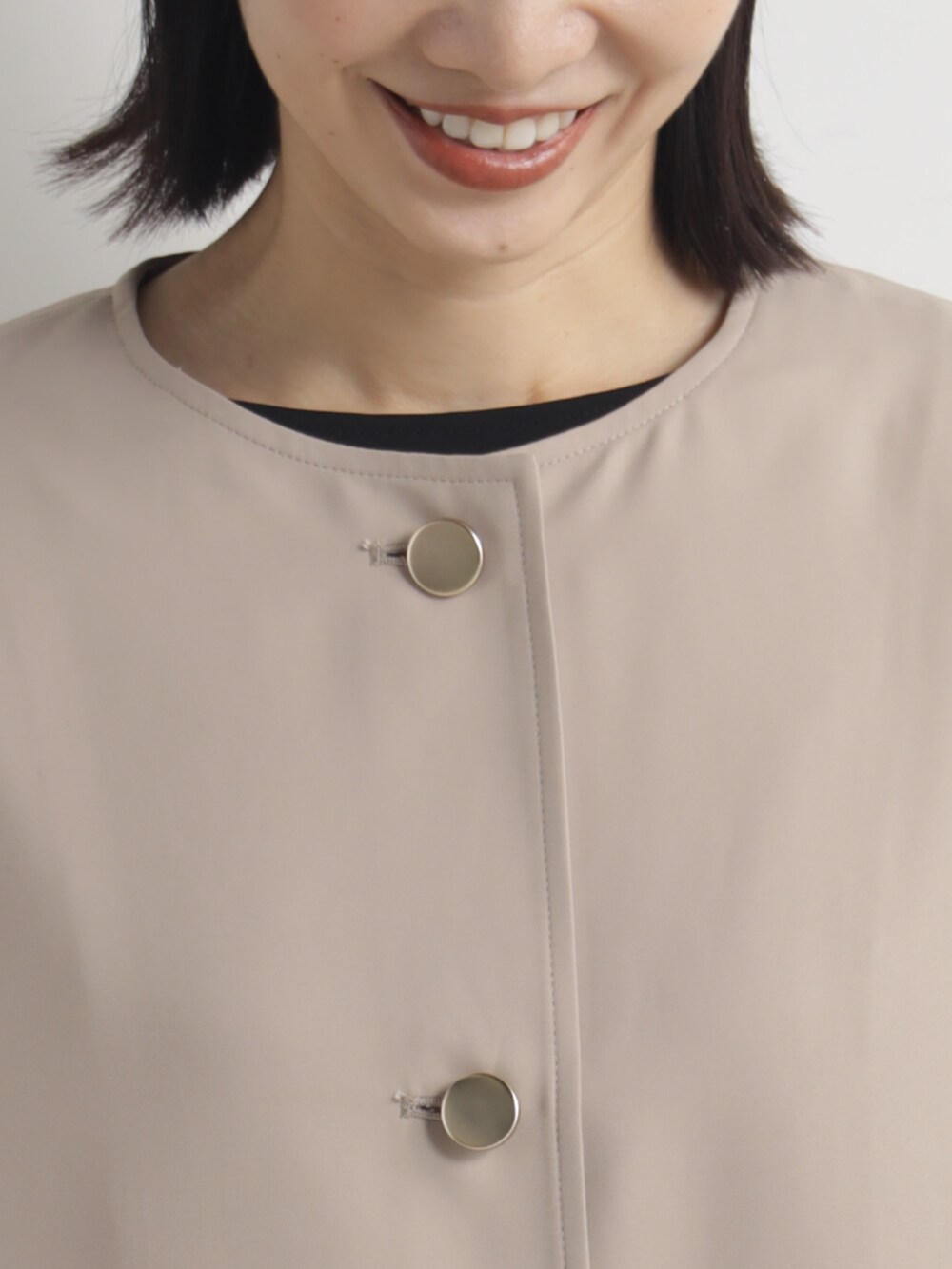 ベージュ系のノーカラーコートを着用したレディースの春コーディネートの3枚目の写真