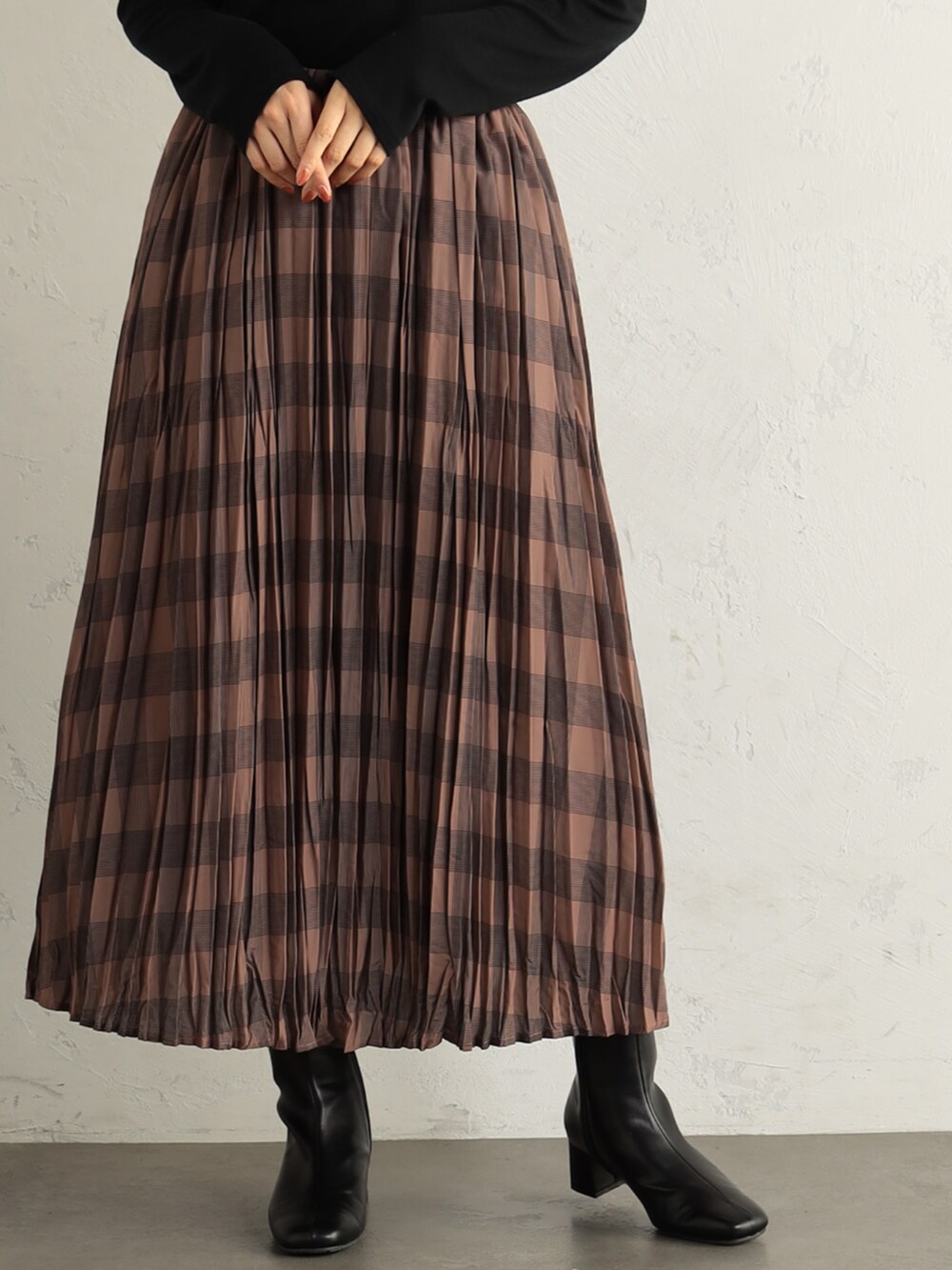 ブラック系のブーツ、ブラック系のニット/セーター、ブラウン系のスカートを着用したレディースの冬コーディネートの2枚目の写真