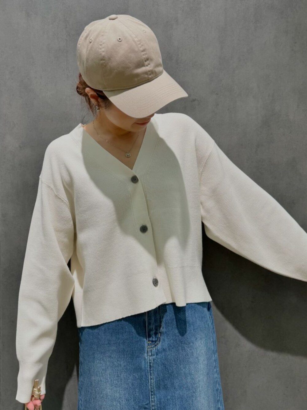 ホワイト系のカーディガン/ボレロ、ブルー系のスカート、ベージュ系のショルダーバッグを着用したレディースの秋コーディネートの2枚目の写真