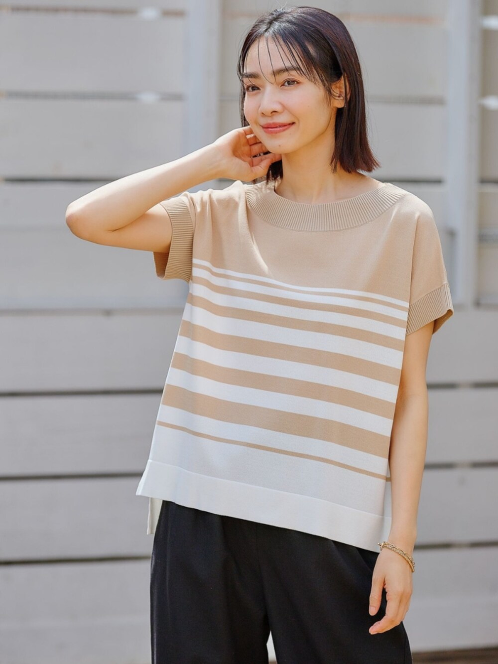 ブラウン系のニット/セーターを着用したレディースの夏コーディネートの2枚目の写真