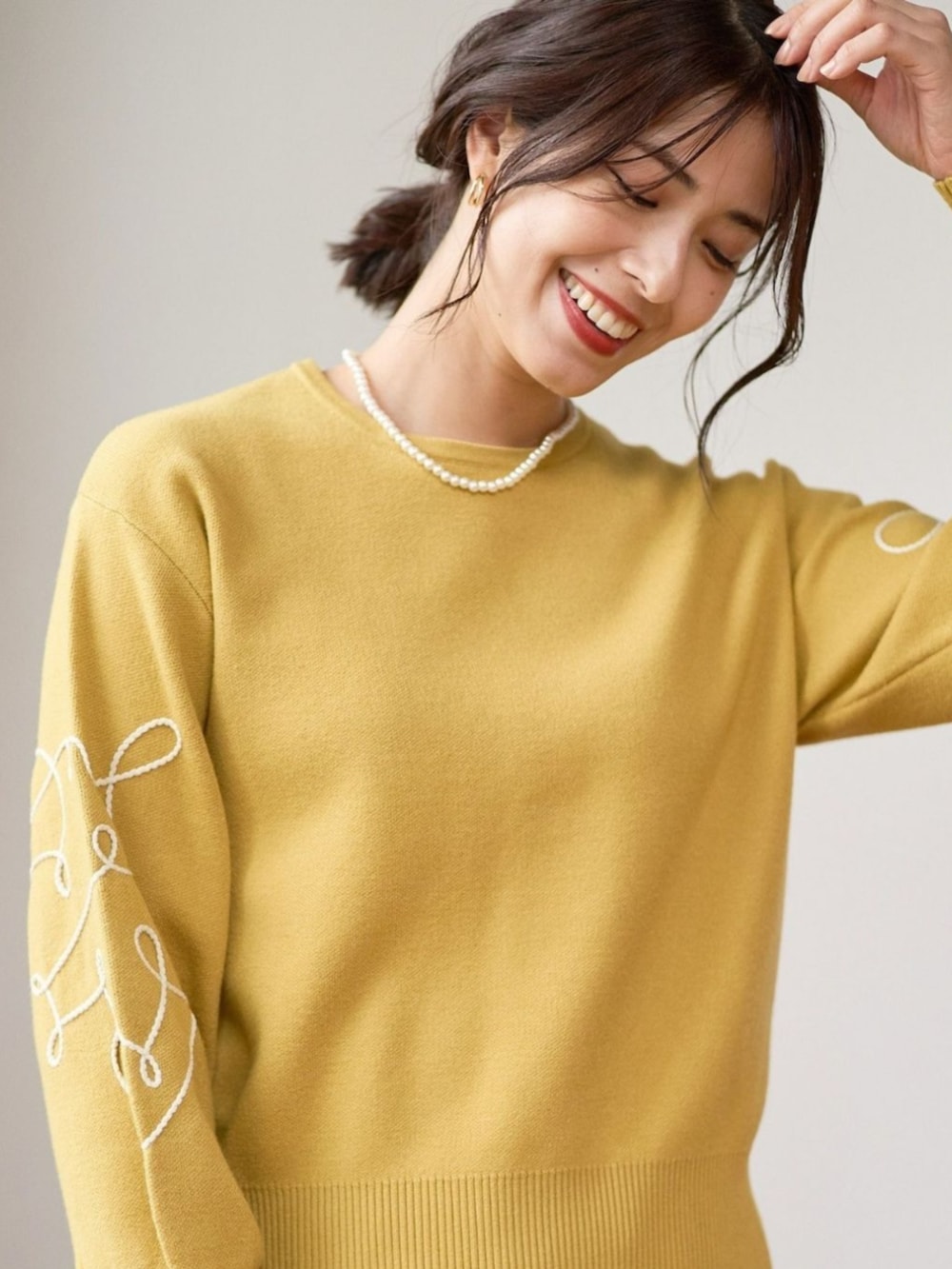 イエロー系のニット/セーターを着用したレディースの冬コーディネートの3枚目の写真