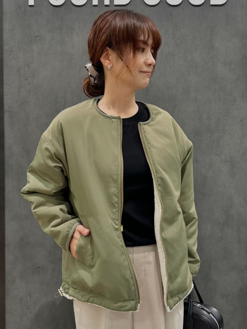 グリーン系のブルゾン、ベージュ系のチノパンツを着用したレディースの秋コーディネートの2枚目の写真