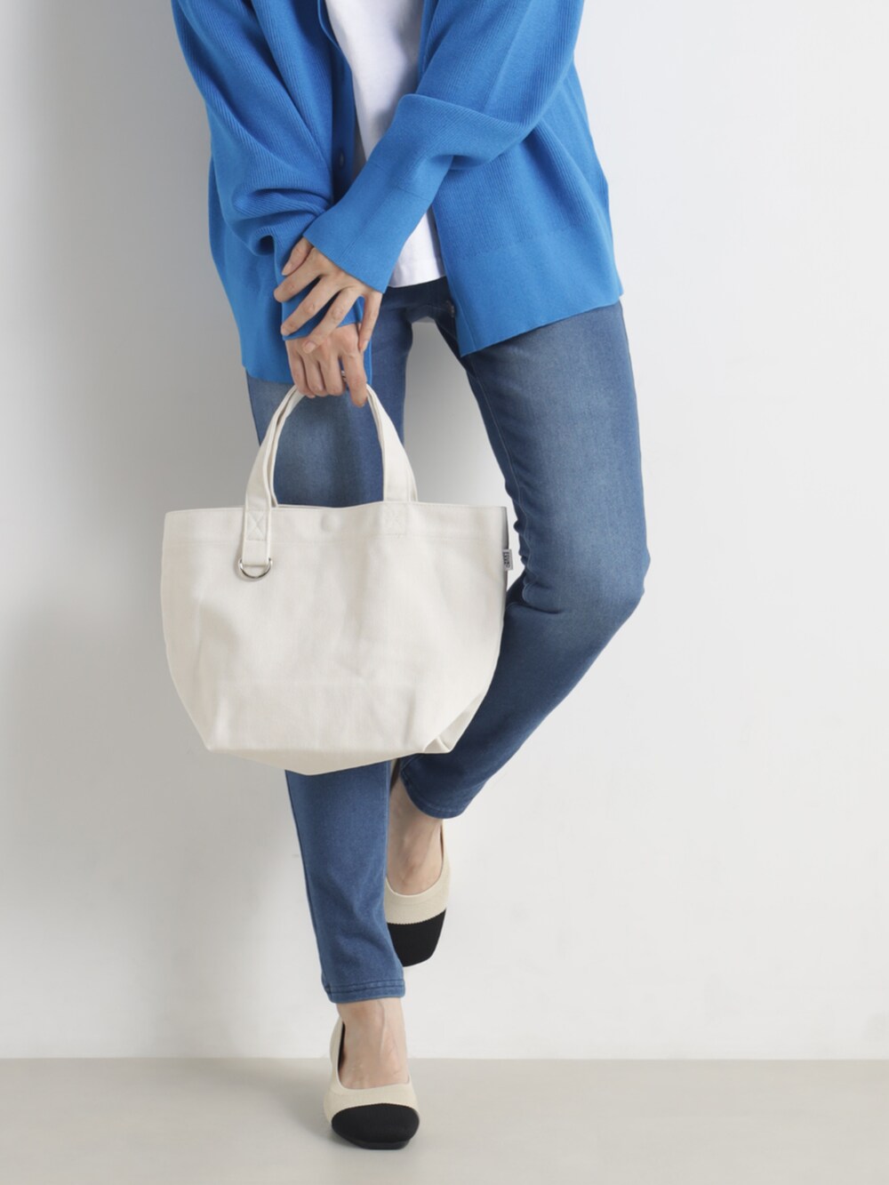 ブルー系のトップス、ベージュ系のトートバッグ、ベージュ系のその他シューズを着用したレディースの冬コーディネートの2枚目の写真