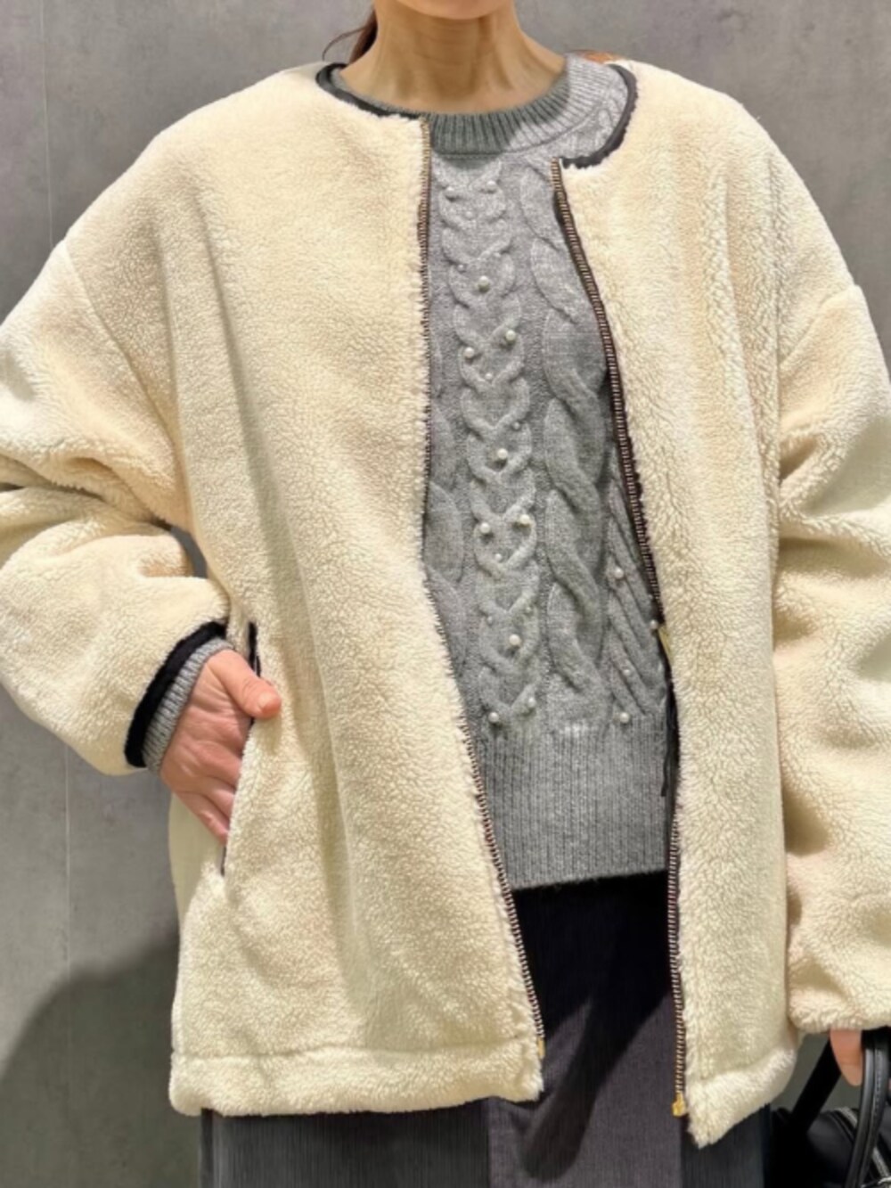 ブラック系のブルゾン、グレー系のニット/セーター、グレー系のスカートを着用したレディースの冬コーディネートの2枚目の写真