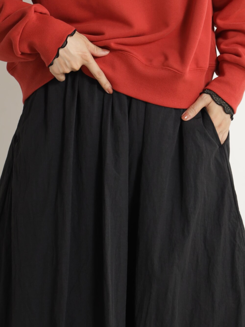 レッド系のスウェット、ブラック系のスカートを着用したレディースの冬コーディネートの3枚目の写真