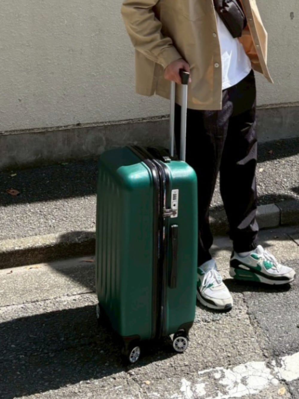 グリーン系のスーツケース/キャリーバッグを着用したメンズの秋コーディネートの2枚目の写真