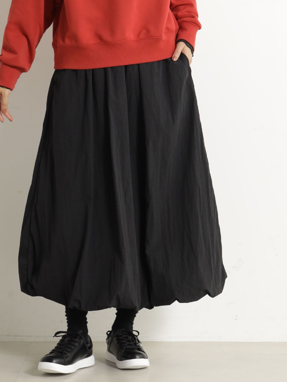 レッド系のスウェット、ブラック系のスカートを着用したレディースの冬コーディネートの2枚目の写真