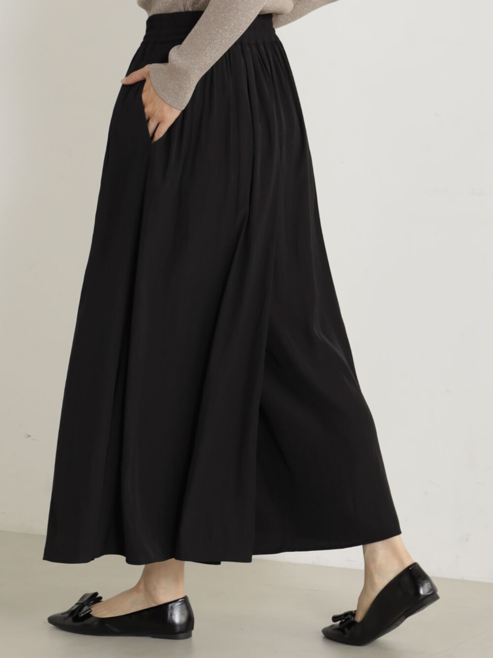 ブラック系のショルダーバッグ、ブラック系のパンプス、ベージュ系のニット/セーターを着用したレディースの冬コーディネートの2枚目の写真