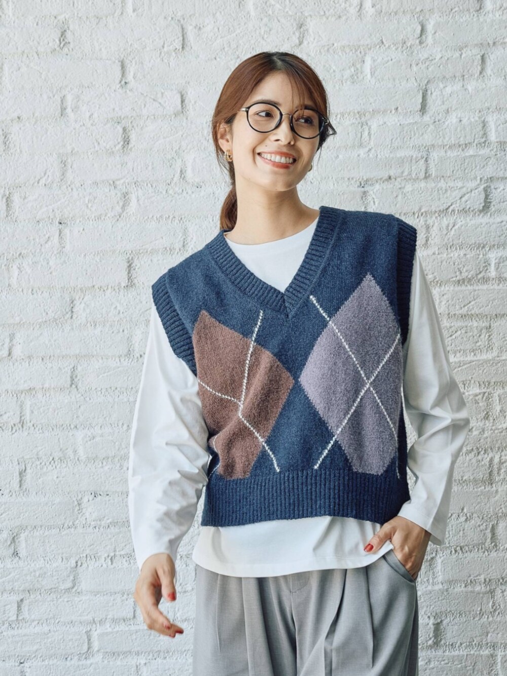ブルー系のベストを着用したレディースの秋コーディネートの2枚目の写真