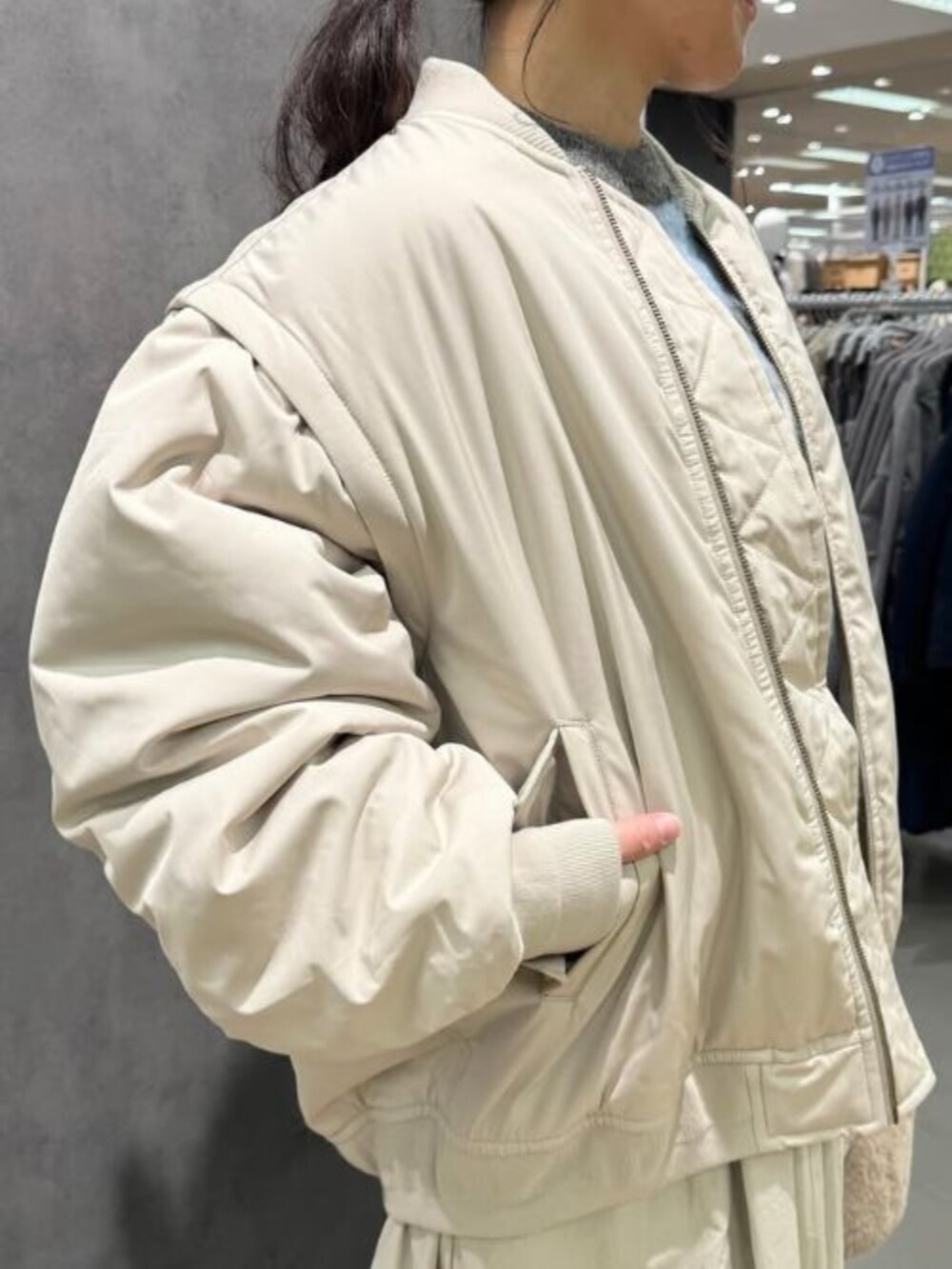 ブルー系のニット/セーター、ベージュ系のスカート、ベージュ系のMA-1を着用したレディースの冬コーディネートの2枚目の写真