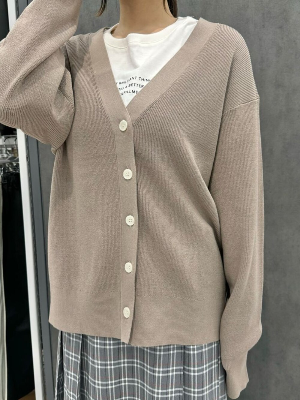 ホワイト系のTシャツ/カットソー、ベージュ系のカーディガン/ボレロ、グレー系のスカートを着用したレディースの秋コーディネートの2枚目の写真