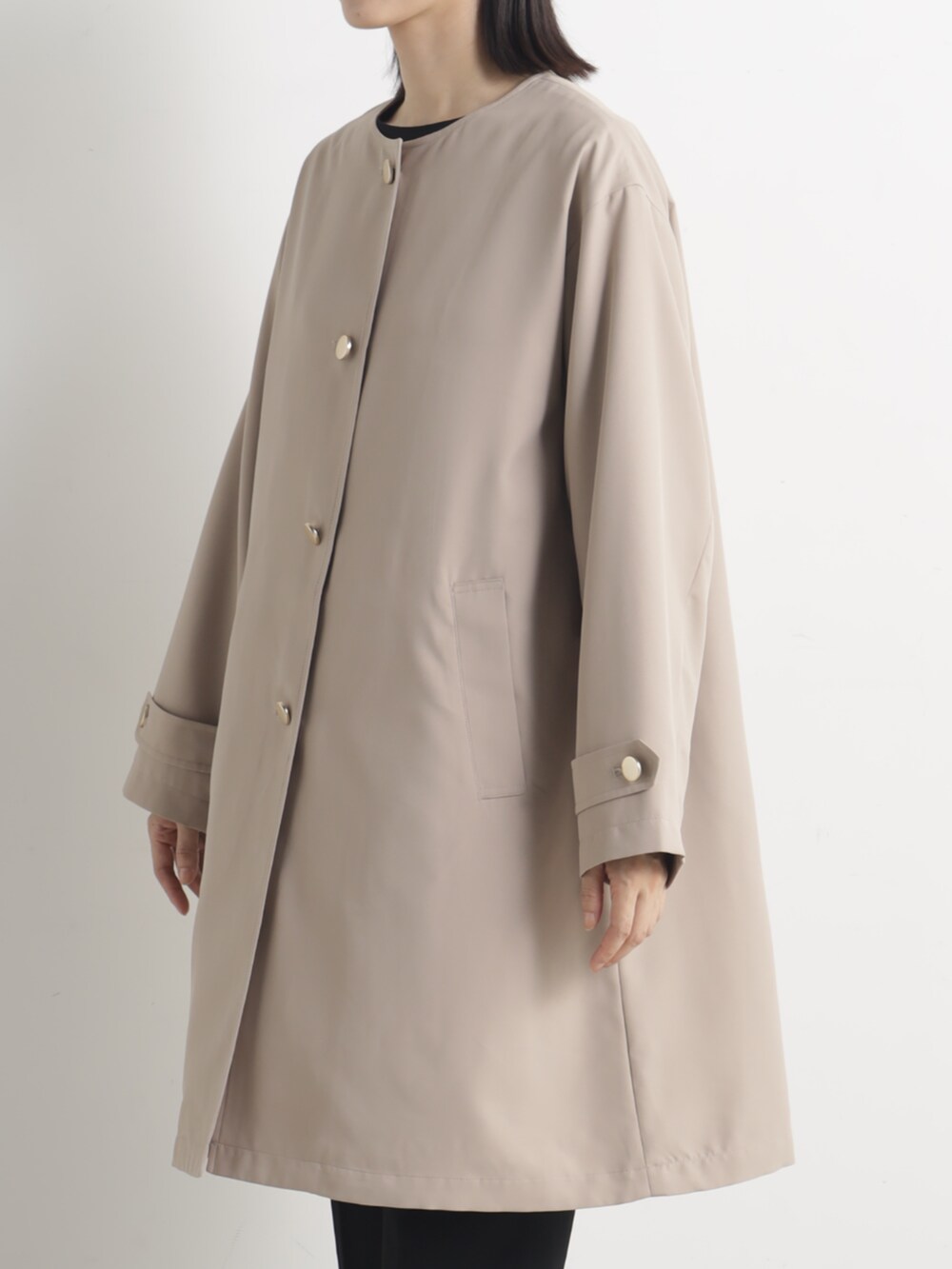 ベージュ系のノーカラーコートを着用したレディースの春コーディネートの2枚目の写真