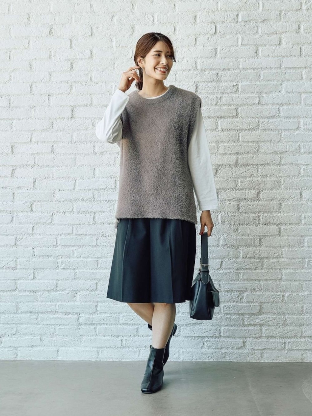 グレー系のベストを着用したレディースの秋コーディネートの2枚目の写真