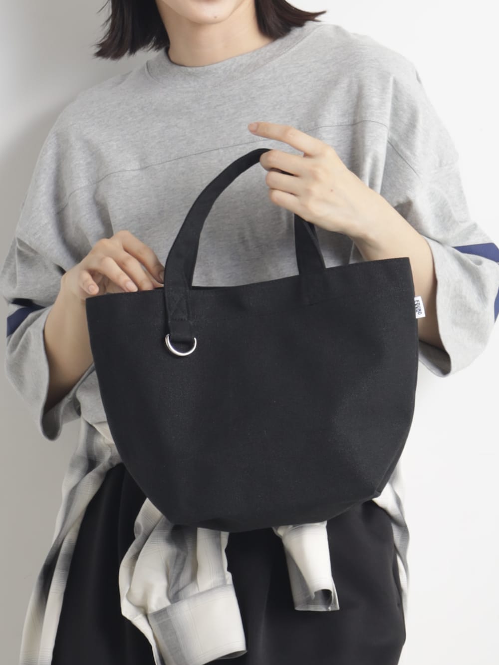 ブラック系のトートバッグを着用したレディースの春コーディネートの2枚目の写真