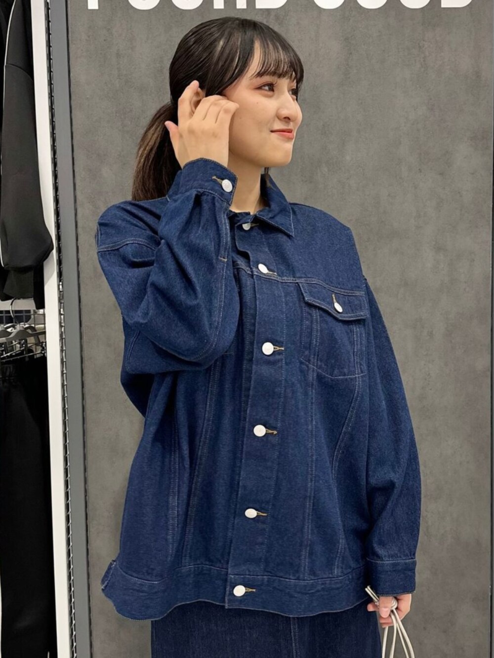 ブルー系のスカート、グレー系のショルダーバッグ、ブルー系のデニムジャケットを着用したレディースの秋コーディネートの2枚目の写真