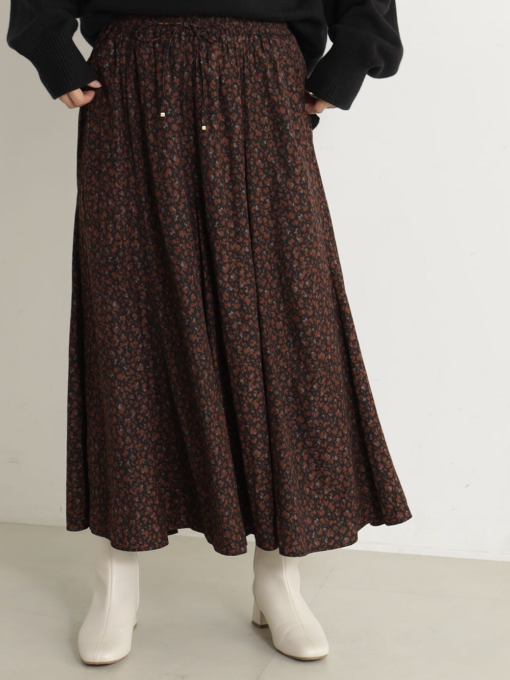 ピンク系のショルダーバッグ、ベージュ系のブーツ、ブラック系のニット/セーターを着用したレディースの冬コーディネートの5枚目の写真