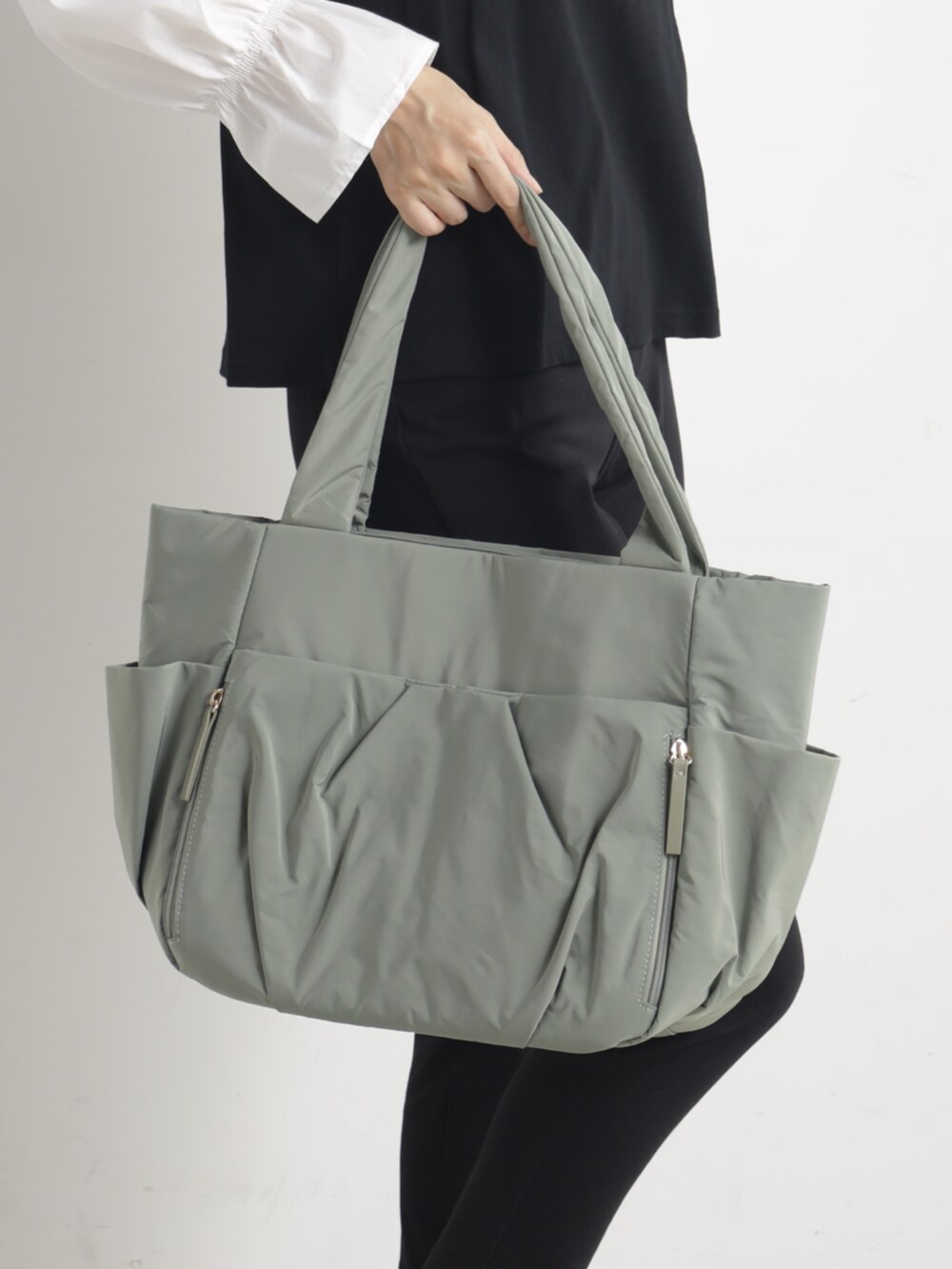 グリーン系のトートバッグを着用したレディースの冬コーディネートの2枚目の写真