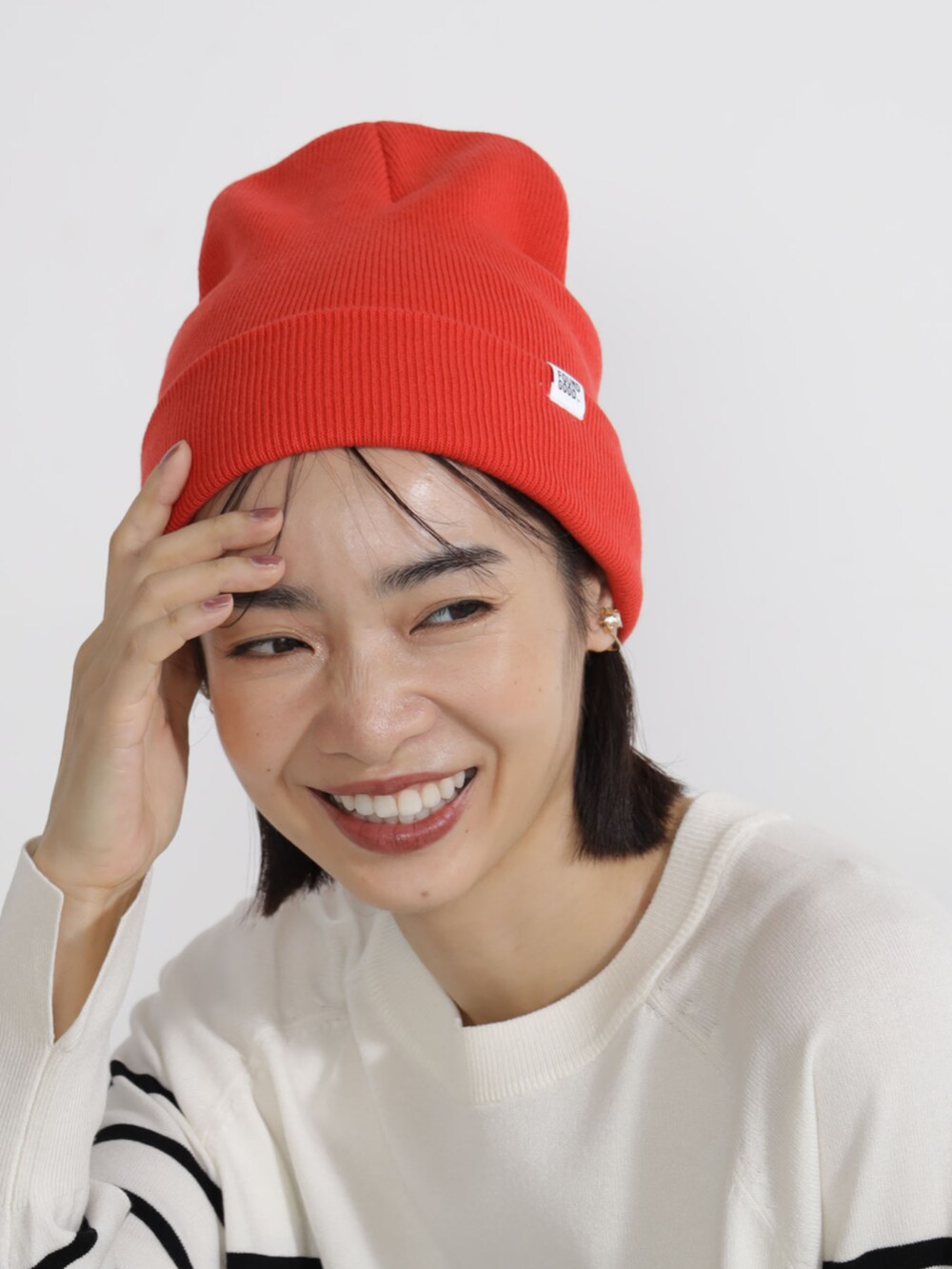 グレー系のニット/セーター、オレンジ系のキャップを着用したレディースの秋コーディネートの2枚目の写真