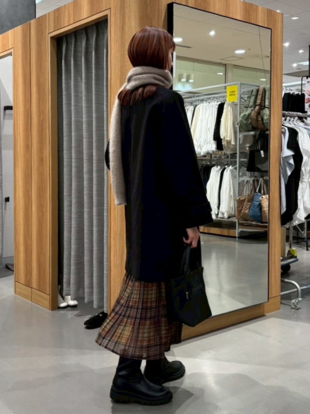 ブラック系のノーカラーコートを着用したレディースの冬コーディネートの2枚目の写真