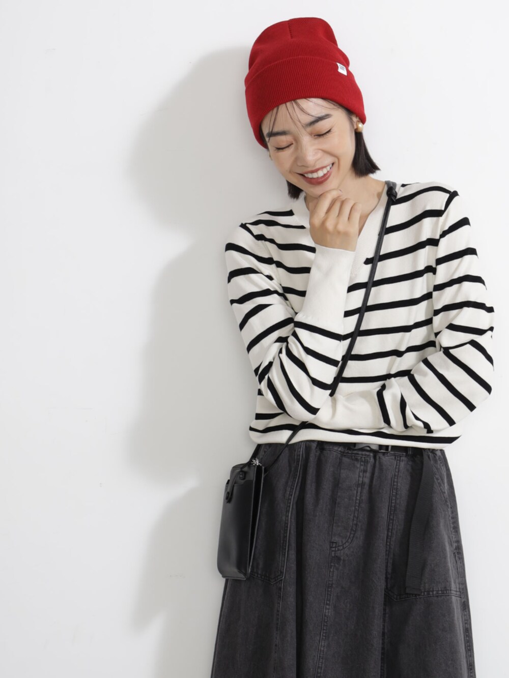 グレー系のニット/セーター、レッド系のキャップを着用したレディースの秋コーディネートの2枚目の写真