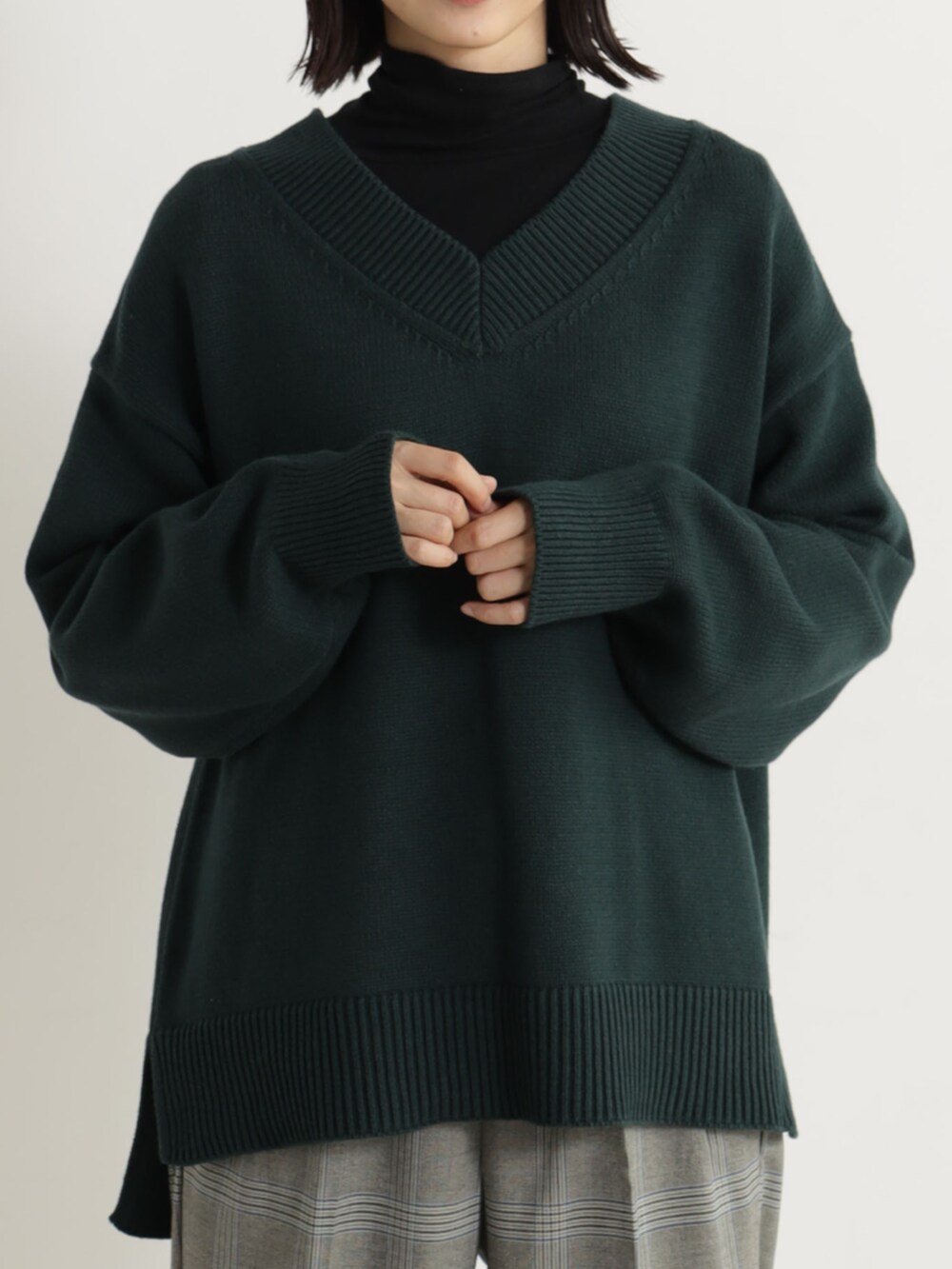 ブラック系のパンプス、ブルー系のその他パンツ、グリーン系のチュニックを着用したレディースの冬コーディネートの2枚目の写真