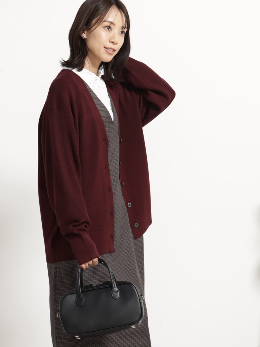 ブラック系のブーツ、ブラック系のボストンバッグ、レッド系のカーディガン/ボレロを着用したレディースの秋コーディネートの2枚目の写真