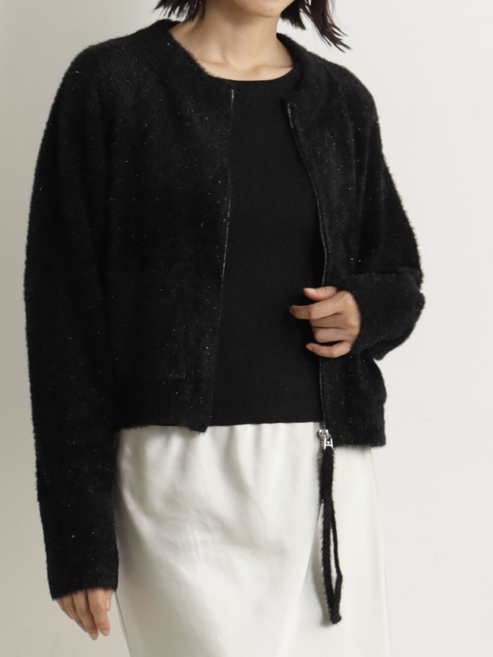 ベージュ系のブーツ、ベージュ系のスカート、ブラック系のカーディガン/ボレロを着用したレディースの冬コーディネートの2枚目の写真