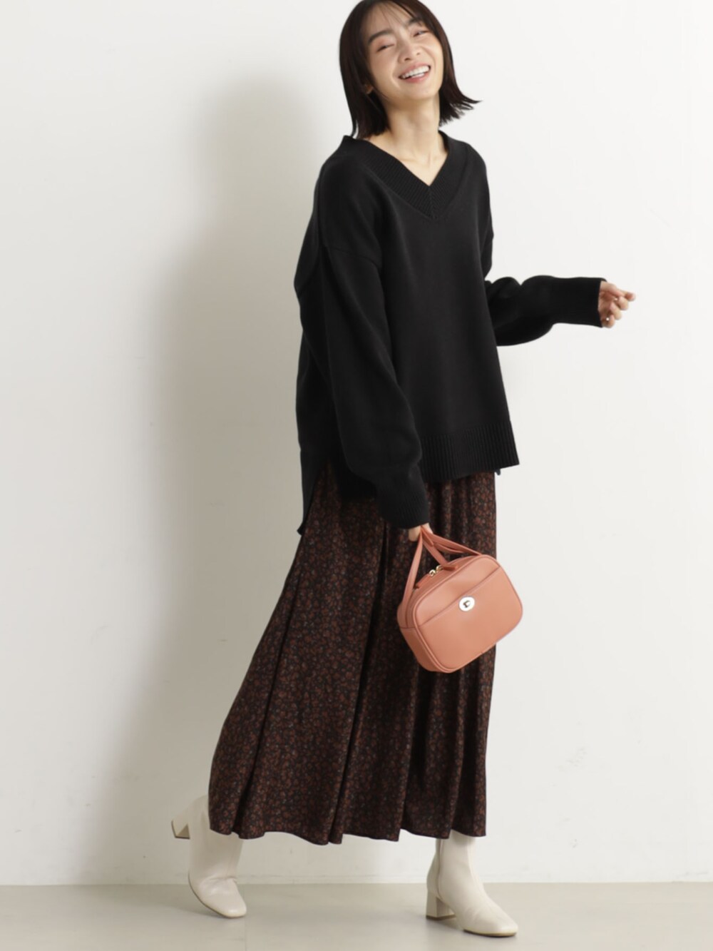 ピンク系のショルダーバッグ、ベージュ系のブーツ、ブラック系のニット/セーターを着用したレディースの冬コーディネートの2枚目の写真