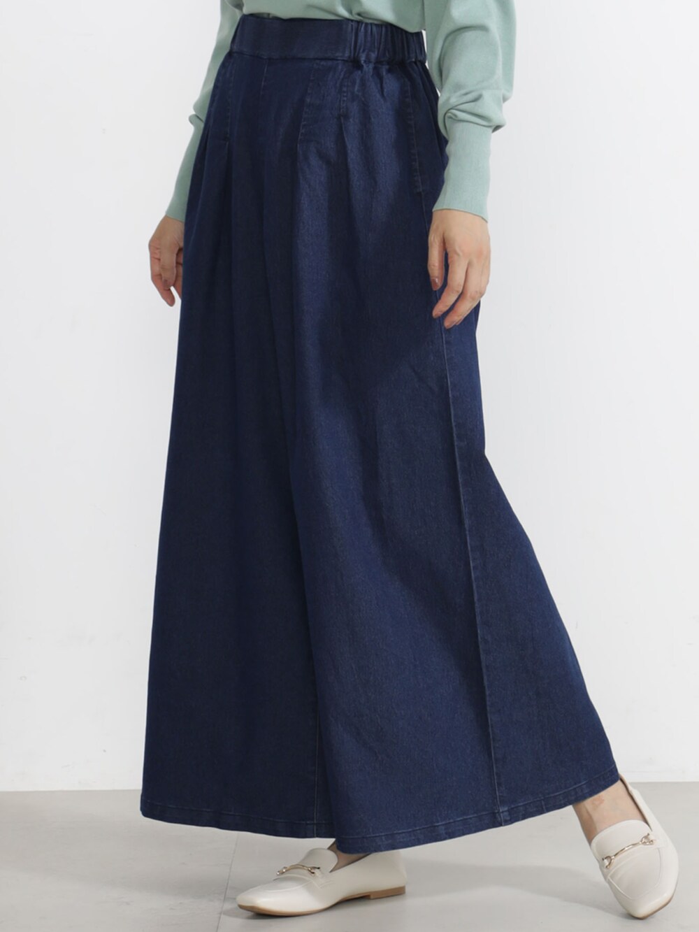 グリーン系のニット/セーター、ベージュ系のチノパンツを着用したレディースの秋コーディネートの2枚目の写真