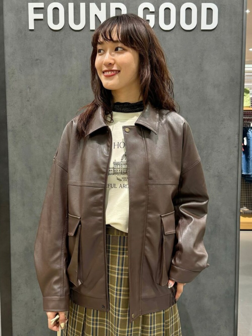 グリーン系のスカート、ブラウン系のブルゾン、ベージュ系のスウェットを着用したレディースの秋コーディネートの2枚目の写真