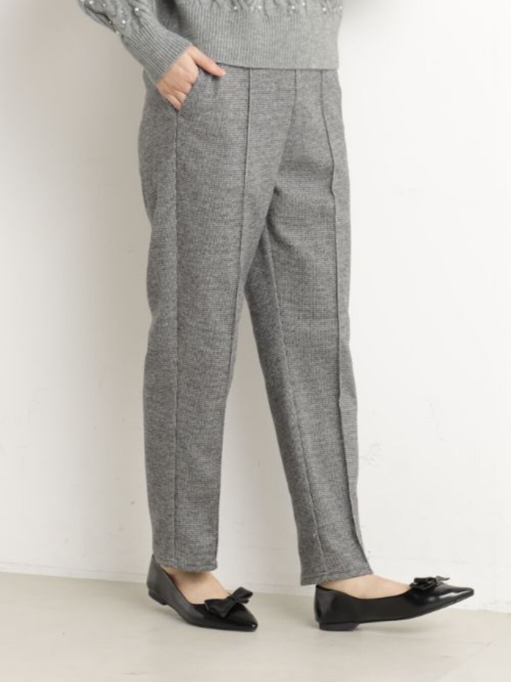 ブラック系のボストンバッグ、ブラック系のパンプス、グレー系のニット/セーターを着用したレディースの冬コーディネートの2枚目の写真