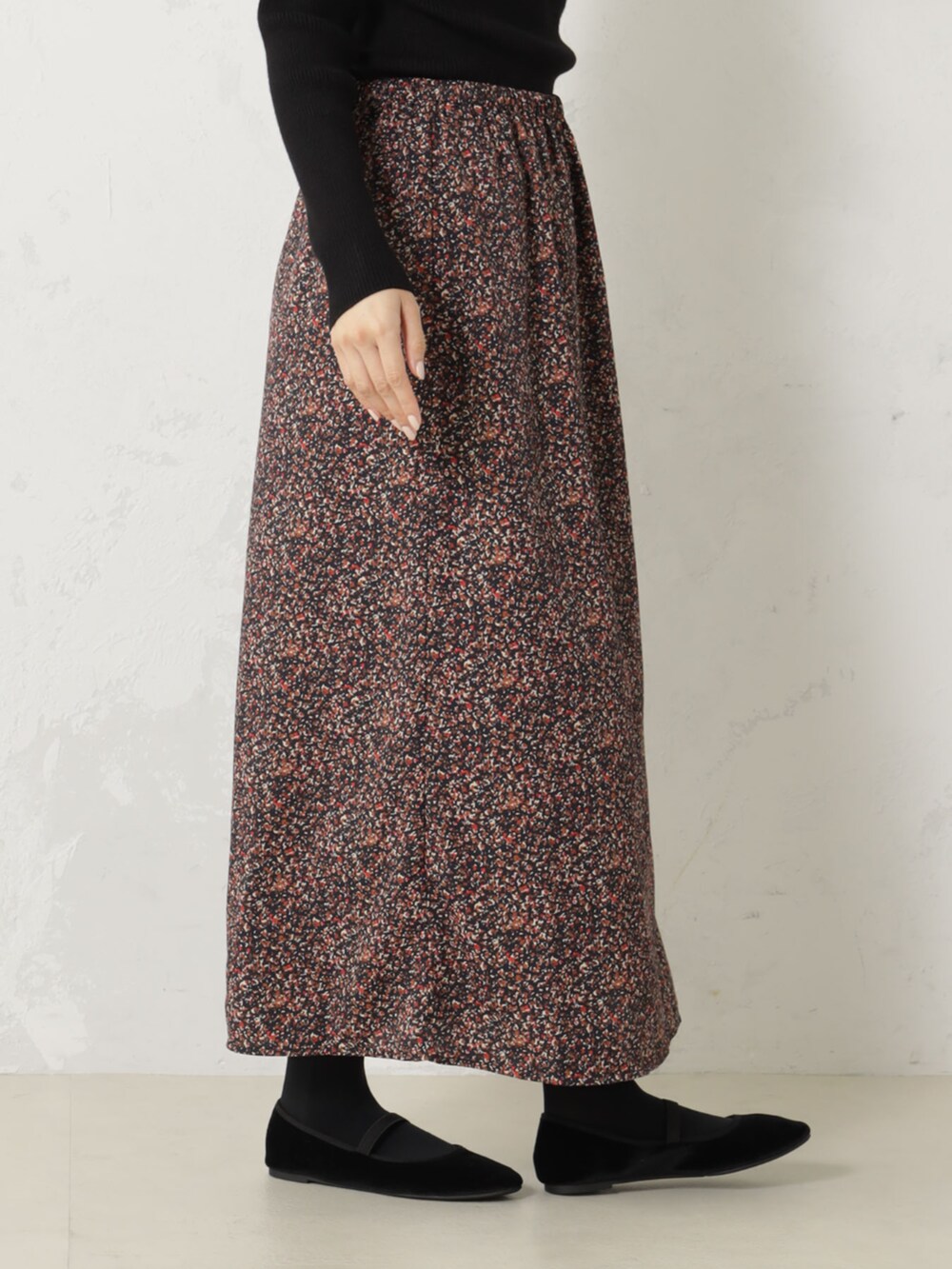 レッド系のスカート、ブラック系のニット/セーターを着用したレディースの秋コーディネートの2枚目の写真