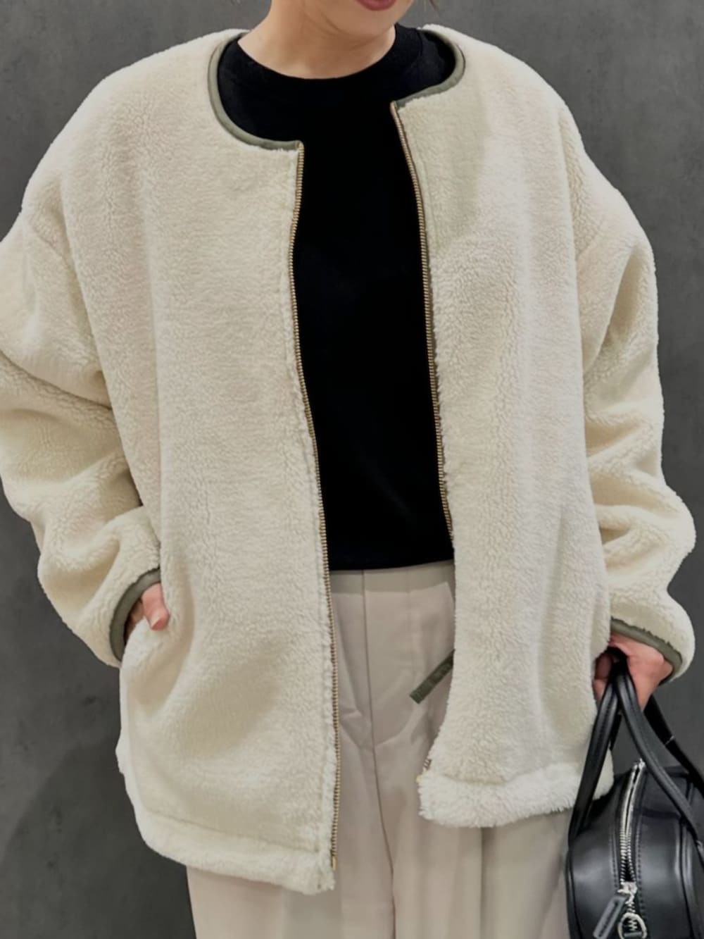 グリーン系のブルゾン、ベージュ系のチノパンツを着用したレディースの秋コーディネートの4枚目の写真