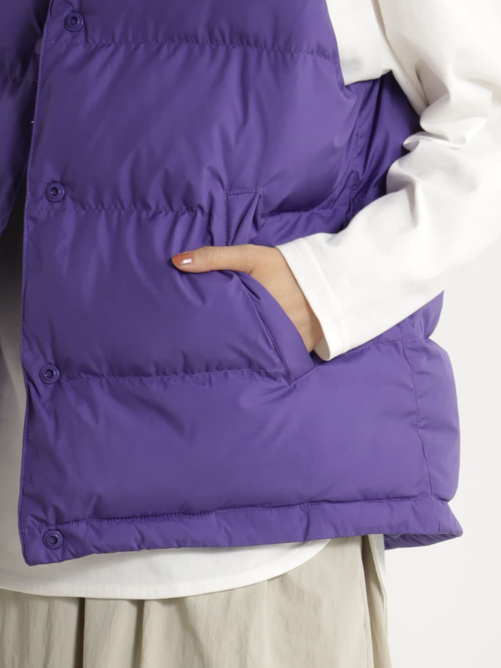 ブラウン系のブーツ、ベージュ系のスカート、パープル系のダウンベストを着用したレディースの冬コーディネートの3枚目の写真