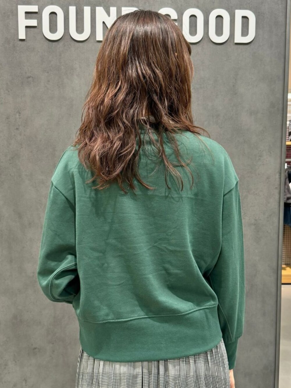 グリーン系のスウェット、グレー系のスカートを着用したレディースの秋コーディネートの2枚目の写真