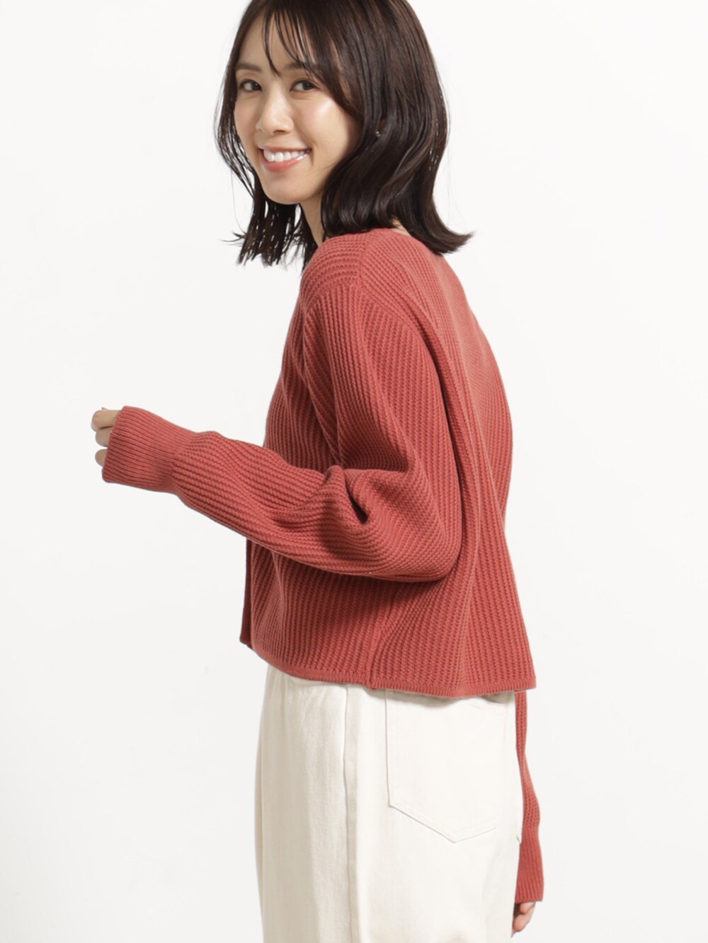 ホワイト系のデニムパンツ、ホワイト系のパンプス、レッド系のカーディガン/ボレロを着用したレディースの秋コーディネートの3枚目の写真