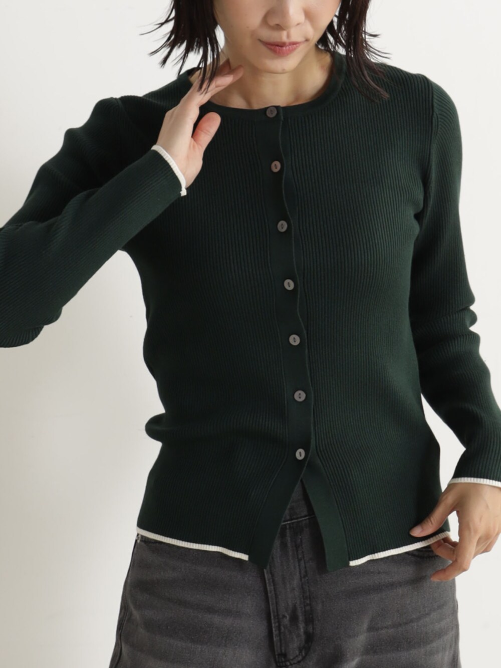 ブラック系のパンプス、グレー系のデニムパンツ、グリーン系のカーディガン/ボレロを着用したレディースの冬コーディネートの2枚目の写真