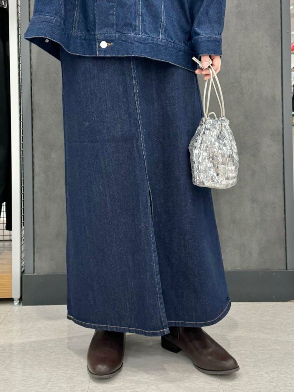 ブルー系のスカート、グレー系のショルダーバッグ、ブルー系のデニムジャケットを着用したレディースの秋コーディネートの3枚目の写真